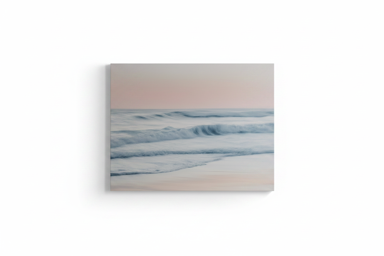 A square canvas wall art print depicting a soft pastel beach seascape with pale pink sky, gentle blue-gray waves, and white surf, shown against a clean white background.