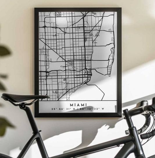 Black Maps 53 by Emiliano Deificus, black-framed artwork above a bicycle; black and white Miami street map with city label.
