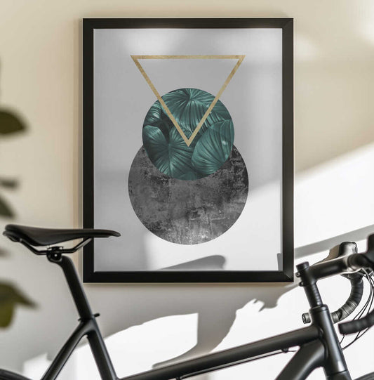Botanical and geometric Shape by Vitor Costa, black-framed artwork above a bicycle; a teal leafy circle overlapping a gray textured circle beneath a gold-colored triangle.