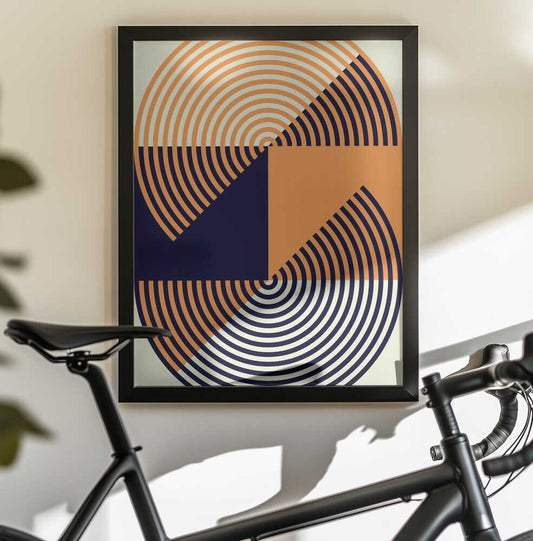 Concentric Circles in Vibrant Orange and Blue by Petr Strnad, black-framed artwork above a bicycle; orange and dark blue concentric arcs divided into bold geometric sections.