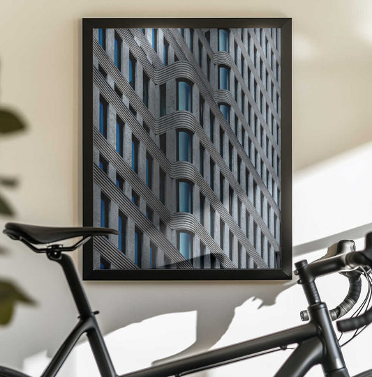 Curvaceous Facade by Stephan Rückert, black-framed print above a bicycle; curved gray building facade with repeating blue-gray windows.