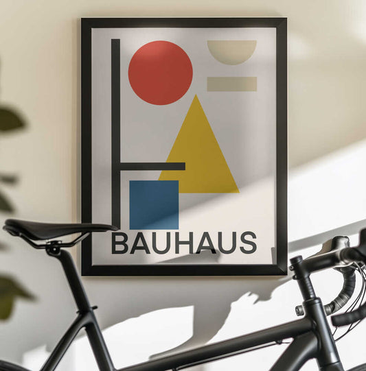 Geometric Bauhaus Design #2 by Little Dean, black-framed artwork above a bicycle; a red circle, yellow triangle, blue block and black lines above BAUHAUS lettering.