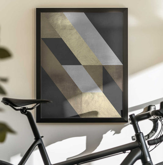 Geometric Gold Flow by Vitor Costa, black-framed artwork above a bicycle; slanting gold-toned and silver-gray bands across a dark geometric background.