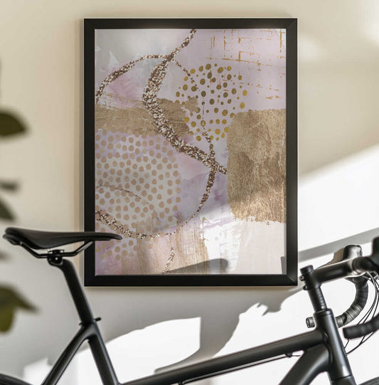 Golden Sunrise-3 by Sally Ann Moss, black-framed artwork above a bicycle; blush abstract fields with gold-toned dots and curved lines.