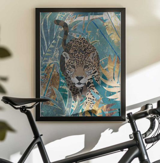 Jaguar Jungle 2 by Sarah Manovski, black-framed artwork above a bicycle; spotted jaguar moving through teal and gold-toned foliage.