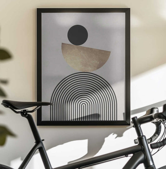 Lines and circles 20 by Vitor Costa, black-framed artwork above a bicycle; a black disc above a tilted gold-toned semicircle and nested black arches.