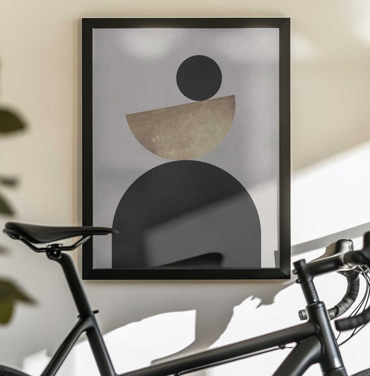 Lines and circles 23 by Vitor Costa, black-framed artwork above a bicycle; a black disc and tilted gold-toned semicircle above a broad black arch.