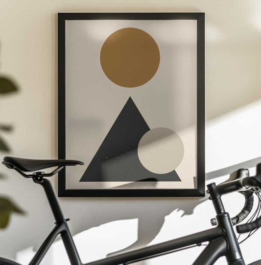 Minimalist geometric composition 03 by Little Dean, black-framed artwork above a bicycle; an ochre circle above a black triangle overlapped by a pale circle.