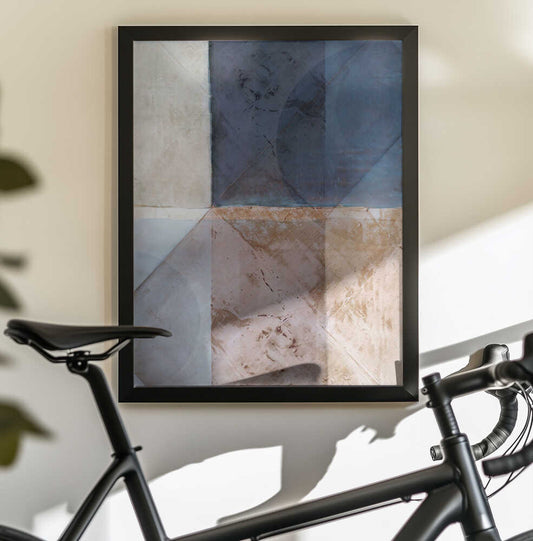 Abstract Geometric Pattern by cartissi, black-framed artwork above a bicycle; layered blue, gray and taupe geometric blocks with diagonal divisions.