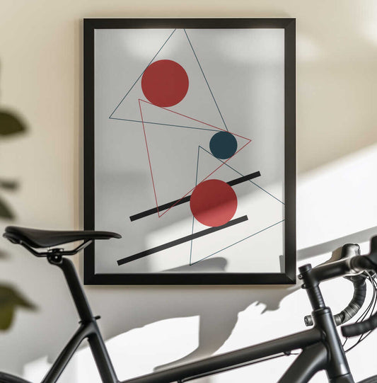 Abstract Geometry by Vesuvik Designs, black-framed artwork above a bicycle; red circles, a small teal disc and thin triangular outlines crossed by black bars.