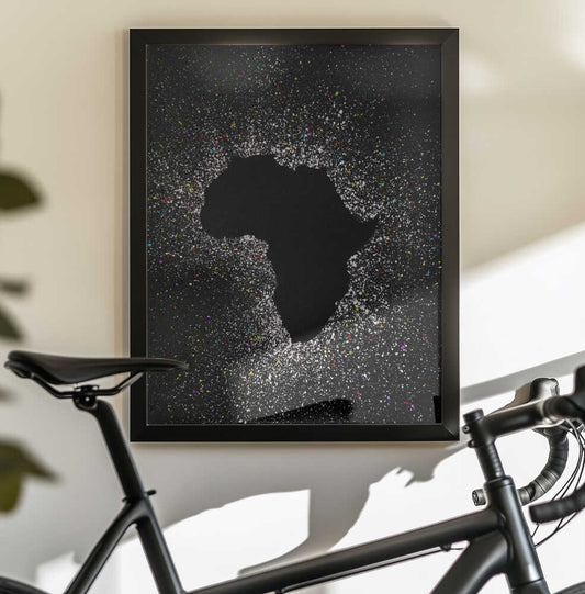 African eclipse effect by Carlo Kaminski, black-framed artwork above a bicycle; dark Africa silhouette surrounded by scattered light-like dots.