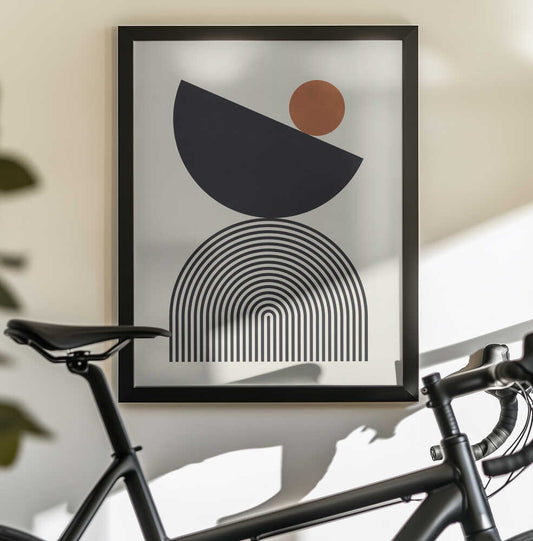 Balance and Curves by Vitor Costa, black-framed artwork above a bicycle; a tilted black semicircle with an orange circle above fine nested black arches.