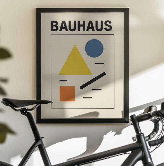 Bauhaus minimalist 06 by Little Dean, black-framed artwork above a bicycle; BAUHAUS lettering above a yellow triangle, blue circle, orange square and black lines.