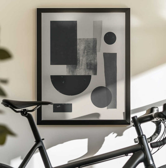 Black geometry collage by Little Dean, in a black frame above a bicycle; black circles, rectangles and a semicircle with textured gray blocks on cream.
