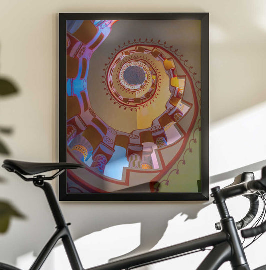 Castle of Bory by Vivien Eszter Váradi - esztevien, black-framed artwork above a bicycle; colorful spiral architecture seen from below.