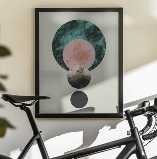 Celestial Harmony by Emanuela Carratoni, black-framed artwork above a bicycle; overlapping teal, dusty pink and gray moon-like circles in a vertical arrangement.