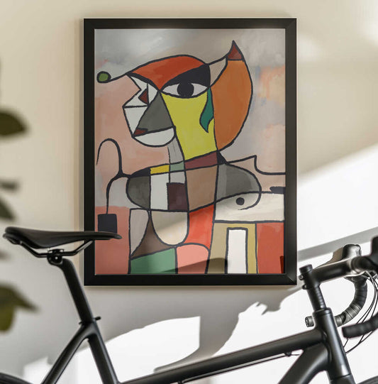 Colorful Geometric Shapes by Little Dean, black-framed artwork above a bicycle; angular abstract portrait with orange, yellow and muted blocks.