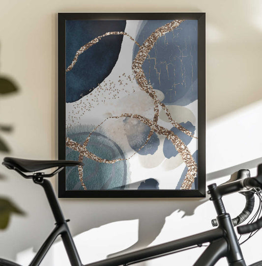 Denim Blue by Sally Ann Moss, black-framed artwork above a bicycle; overlapping denim-blue forms with looping gold-toned lines.