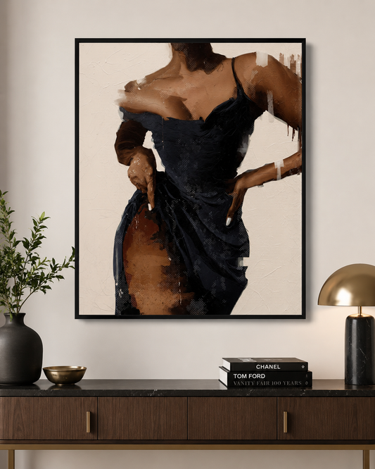 A framed art print featuring a stylized portrait of a woman in a dark dress, displayed on a beige wall above a dark wood console table with a plant, books, and a gold lamp.