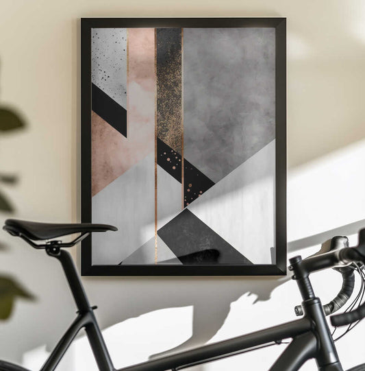 Geo Abstract 1 by Bilge Paksoylu, black-framed artwork above a bicycle; gray, blush and white geometric planes with black accents.