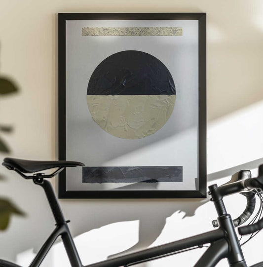 Geometria Y Texturas 2 by David Galan, black-framed artwork above a bicycle; a circle divided into black and pale cream halves between two horizontal bars.