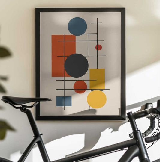 Geometric Abstract Design With Intersecting by Little Dean, black-framed artwork above a bicycle; blue, charcoal, red and yellow circles and rectangles crossed by fine black lines.