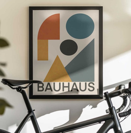 Geometric Bauhaus Composition by Little Dean, black-framed artwork above a bicycle; blue and black circles with rust and gold shapes and BAUHAUS lettering.