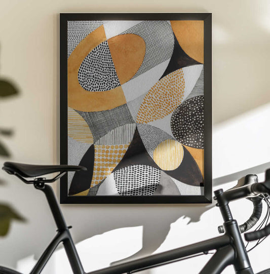 Geometric Harmony by Susan Black, black-framed artwork above a bicycle; overlapping gold, gray and black curved shapes filled with dots and fine patterns.