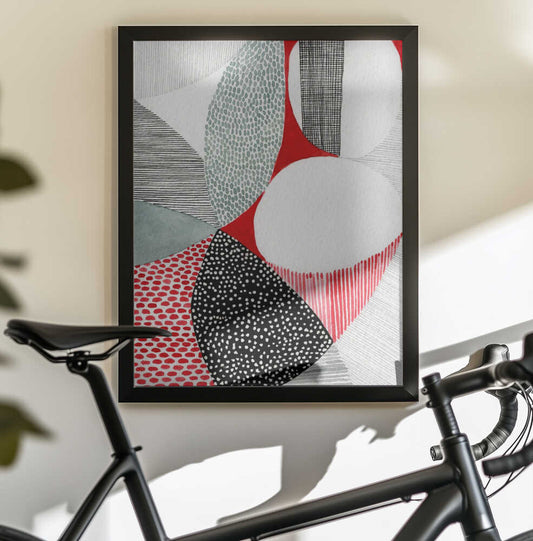 Geometric Patterns And Vivid Colors by Susan Black, black-framed artwork above a bicycle; red, gray, white and black curved shapes filled with dots and linear patterns.