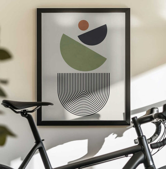 Geometric Shapes in Green Black and Orange by Vitor Costa, black-framed artwork above a bicycle; green and black tilted semicircles beneath a small orange circle above nested U-shaped lines.