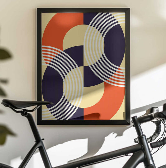 Interwoven Circles by Petr Strnad, black-framed artwork above a bicycle; interlocking orange, cream and dark blue circles crossed by fine pale arcs.