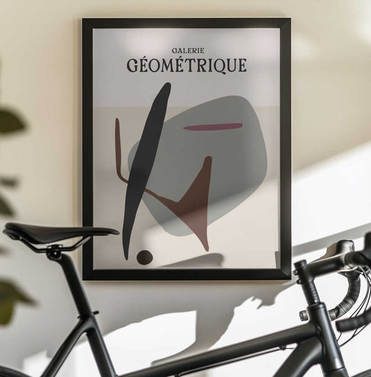 Shapes in Motion by Treechild, black-framed artwork above a bicycle; abstract black, gray and brown shapes beneath GALERIE GÉOMÉTRIQUE lettering.